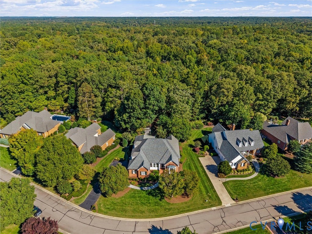 Expansive residential setting with mature trees, manicured lawns, and asphalt roadways
