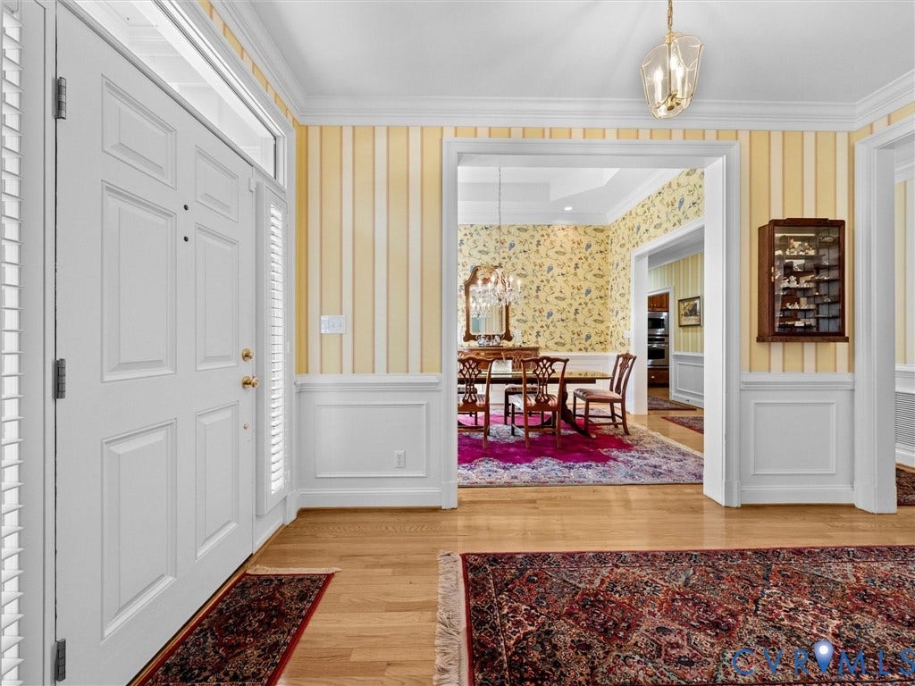 Entryway featuring wood-finish flooring, white paneled doors, wainscoting, and crown molding