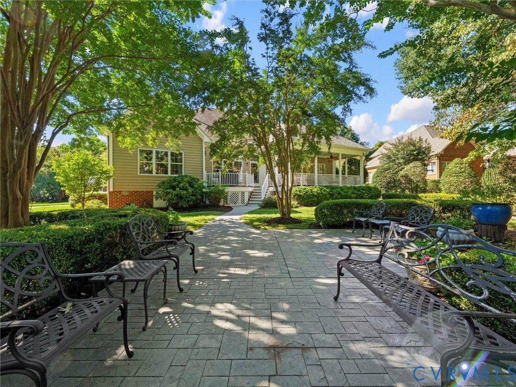 Expansive patio featuring stamped concrete pavers, mature trees, and sculpted hedges