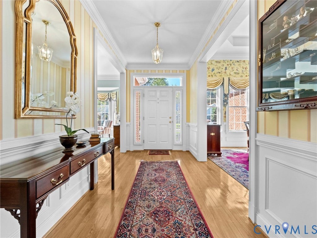 Light wood-finish flooring, white paneled wainscoting, and decorative crown molding