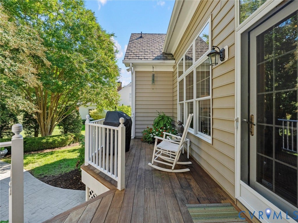 Expansive wood-finish deck with white railings, tan siding, and multi-pane windows