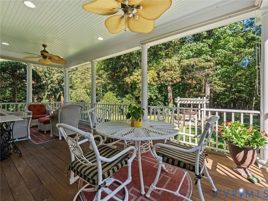 Expansive covered deck featuring wood-finish flooring, white columns, and ceiling fans with integrated lighting