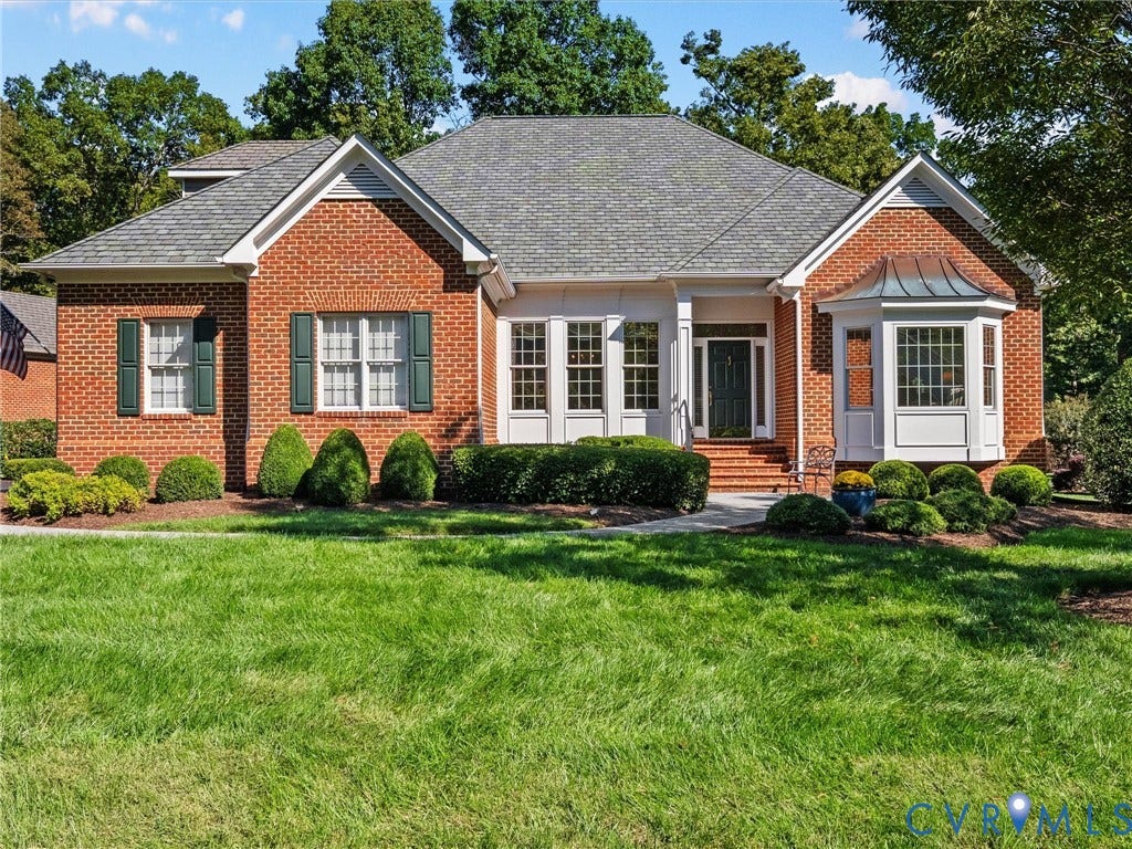 Brick exterior with a gray shingle roof, dark green shutters, and a bay window