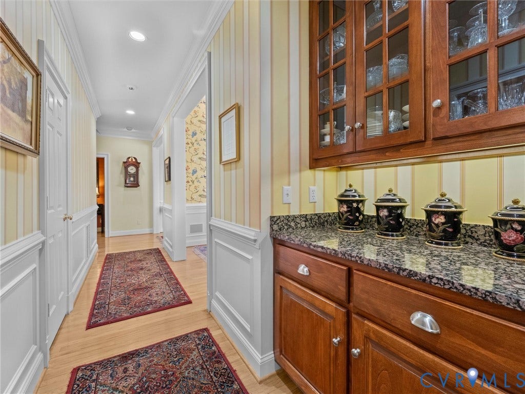 Hardwood flooring, wainscoting, recessed lighting, wood cabinetry, and stone countertop