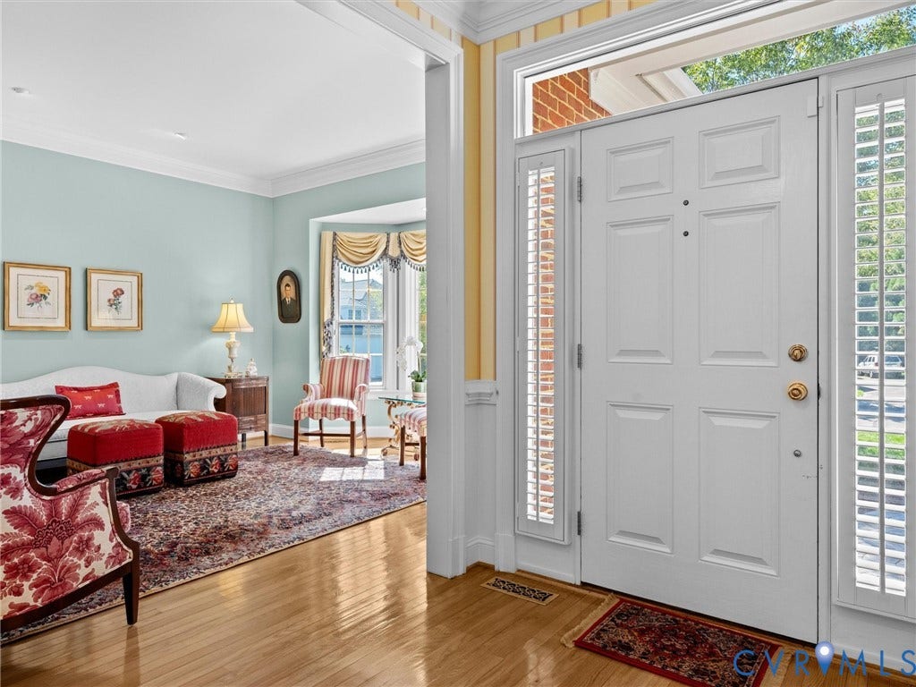 Front entry featuring a paneled door with sidelights and transom window, light wood-finish flooring, and crown molding