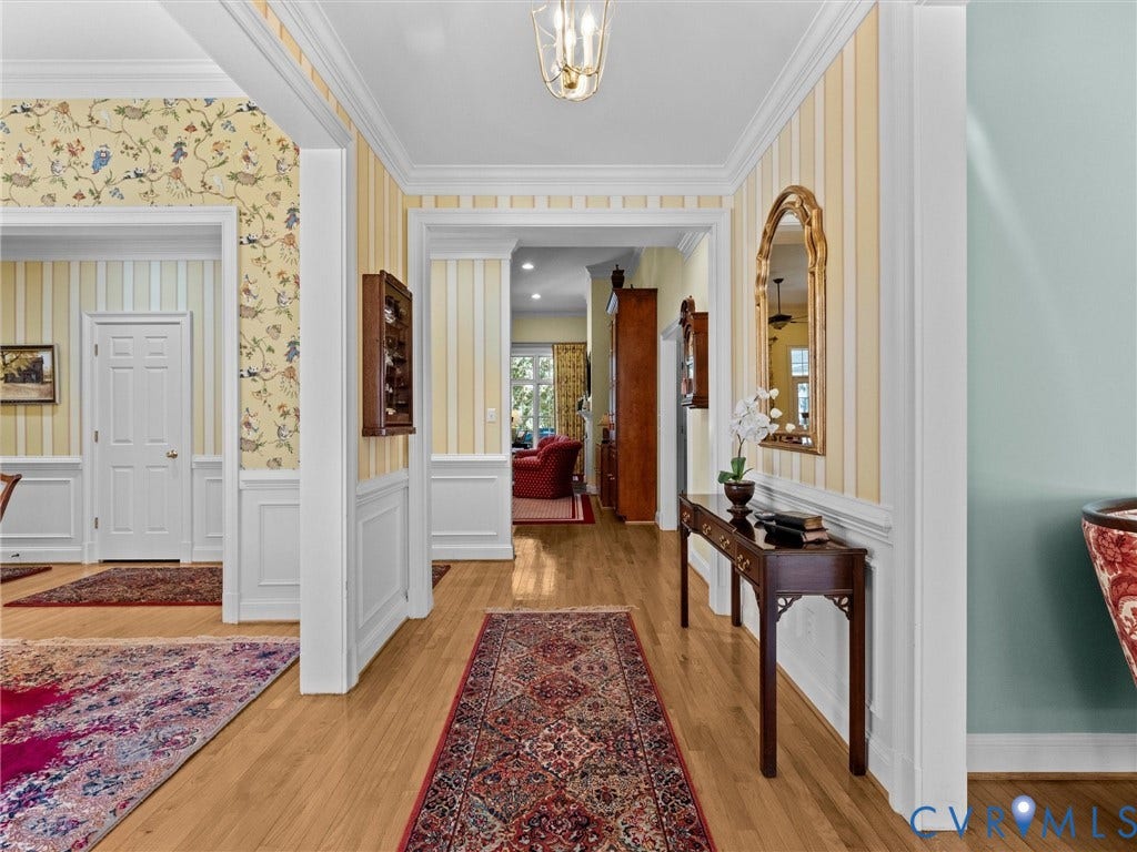 Hardwood flooring, decorative wainscoting, crown molding, and recessed archways
