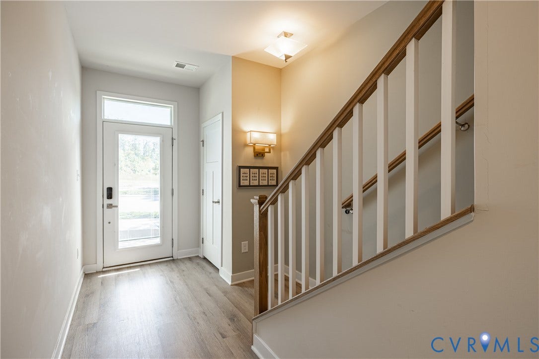 14336 Altavista Boulevard, Midlothian, VA 23114 Light wood-finish flooring, glass-paneled entry door with transom window, white painted walls, wood and white baluster staircase, and a wall-mounted brass sconce