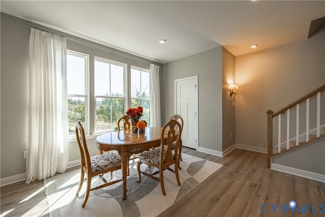 14336 Altavista Boulevard, Midlothian, VA 23114 Bright dining area featuring multiple glass-panel doors and windows with flowing drapery, wood-finish flooring, and a round wood dining table with upholstered chairs