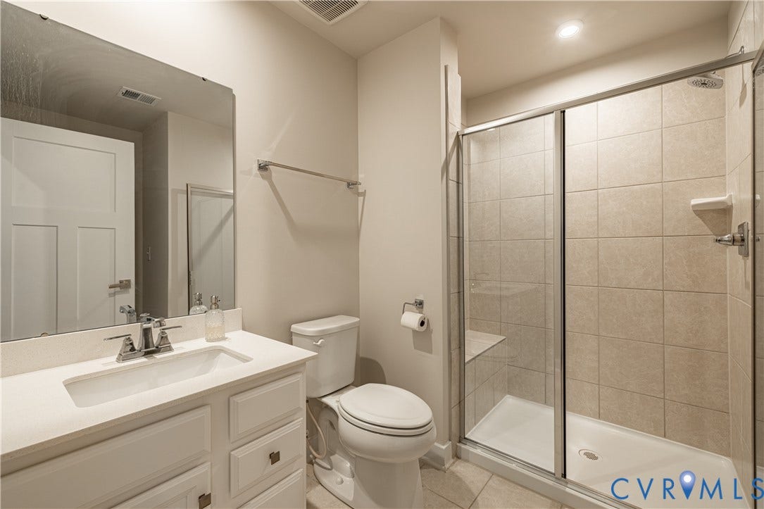 14336 Altavista Boulevard, Midlothian, VA 23114 Modern bathroom featuring a floating vanity with rectangular vessel sink and chrome faucet, quartz countertop, large framed mirror, ceramic tile shower enclosure with glass sliding doors, and ceramic tile flooring throughout