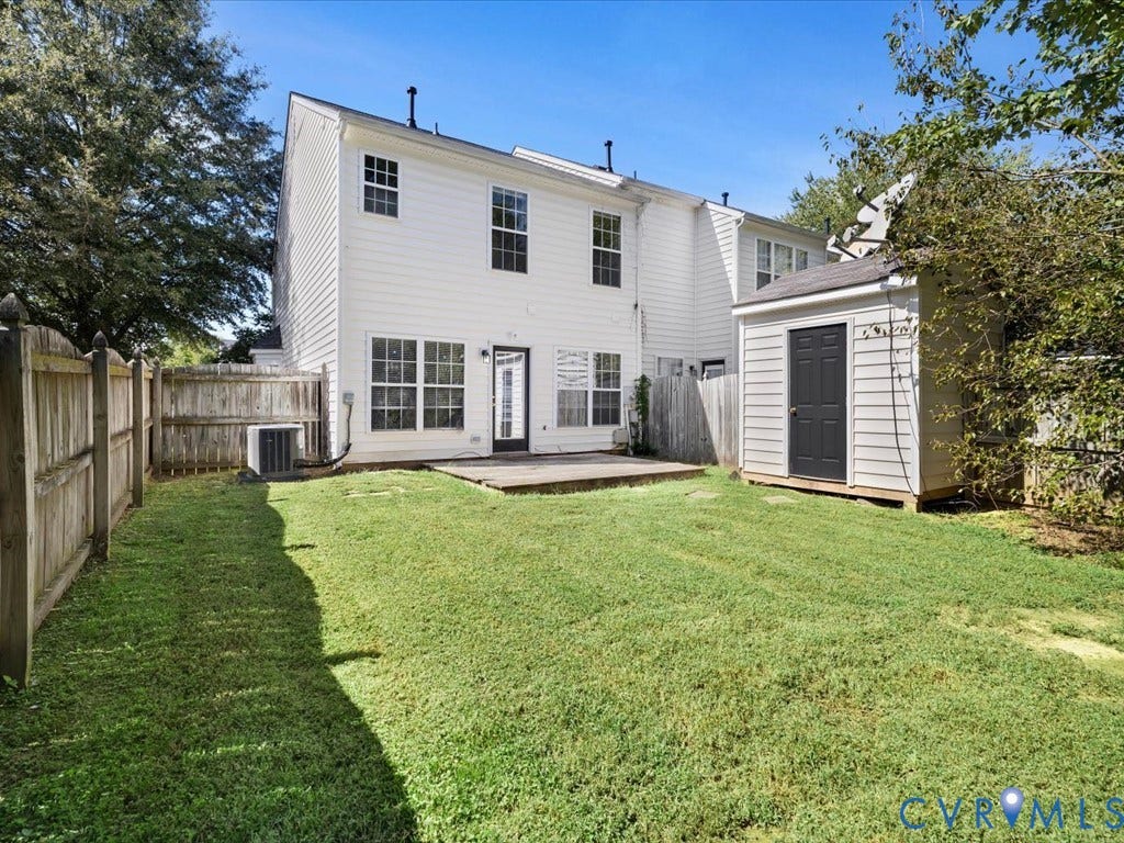 Expansive backyard featuring a manicured lawn, wood fencing, a storage shed, and a private patio