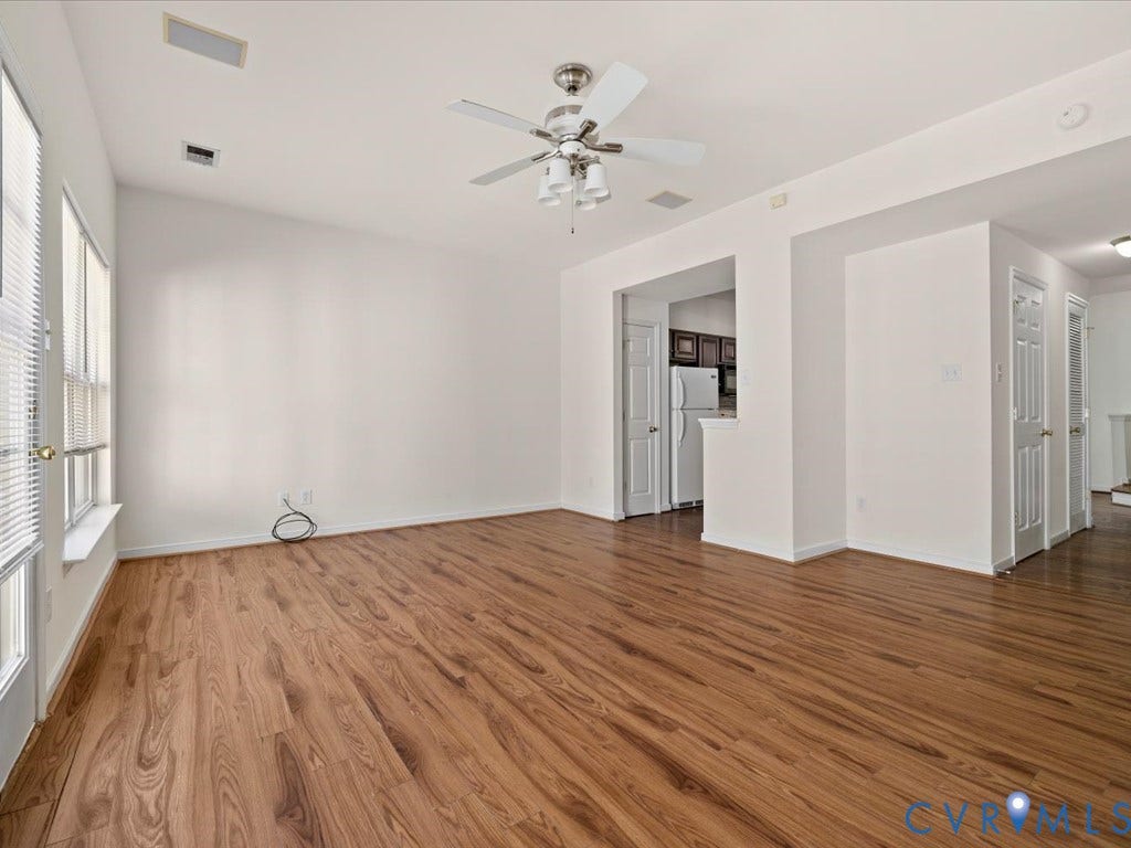 Wood-finish flooring, ceiling fan with integrated lighting, multiple windows, and white interior doors
