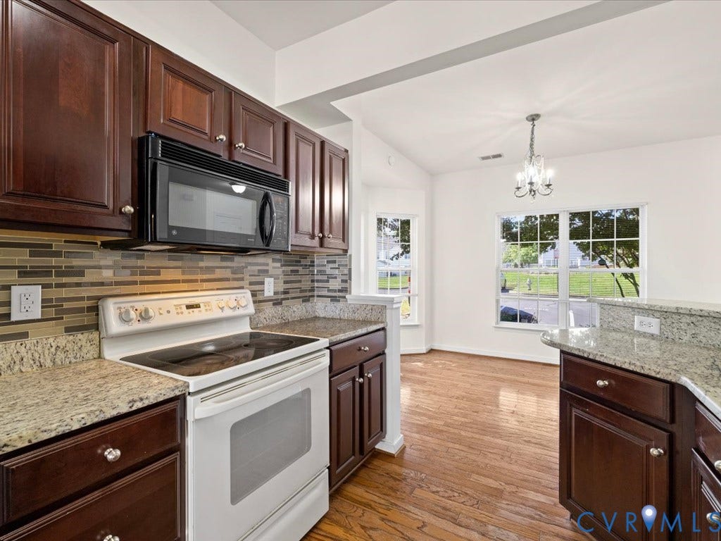 Kitchen featuring wood-finish flooring, dark wood cabinetry, and light-colored countertops
