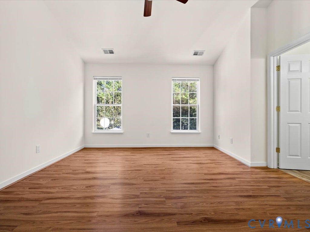 Wood-finish flooring, white walls, and two windows provide natural light