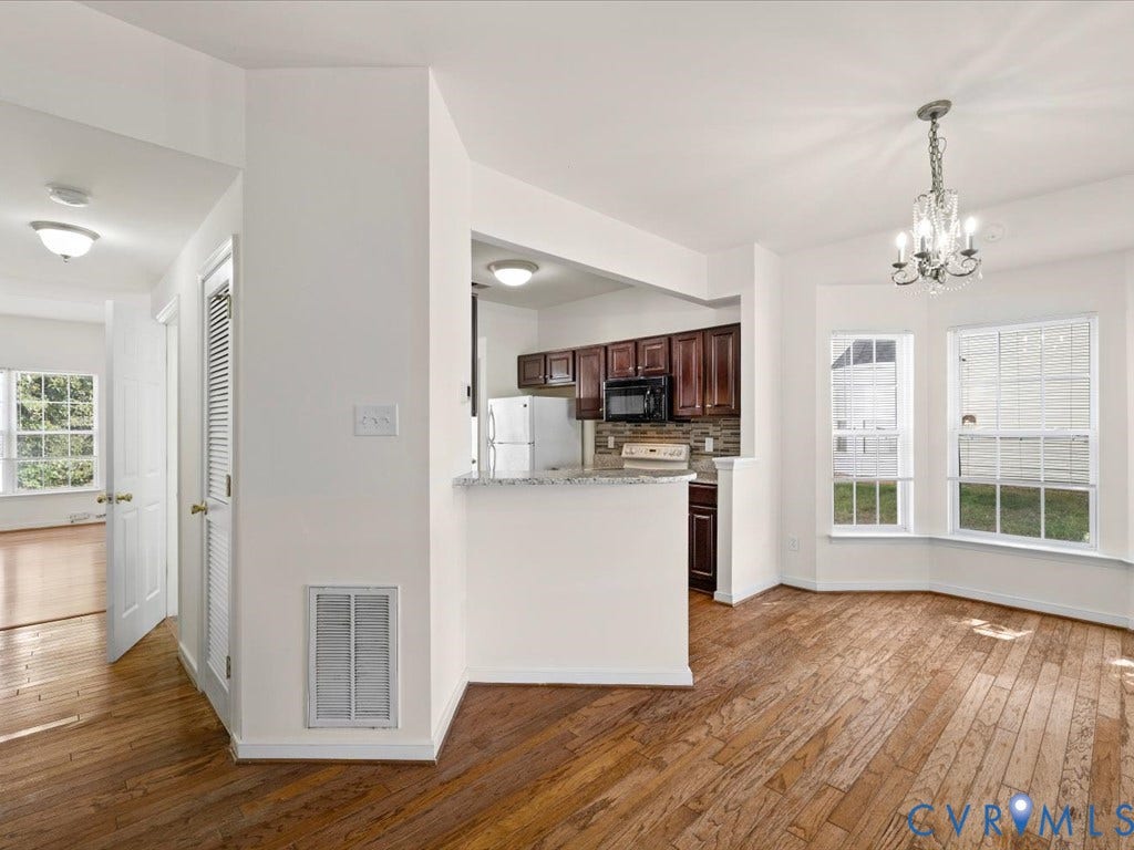 Hardwood flooring, kitchen with dark wood-finish cabinetry, granite-finish counter, stainless steel refrigerator, and built-in microwave