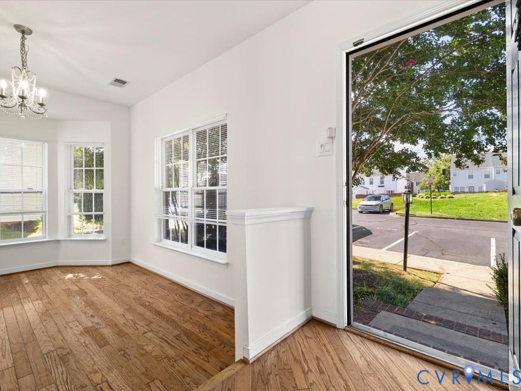 Hardwood-style flooring throughout, bay windows, multiple large windows, and an elegant chandelier