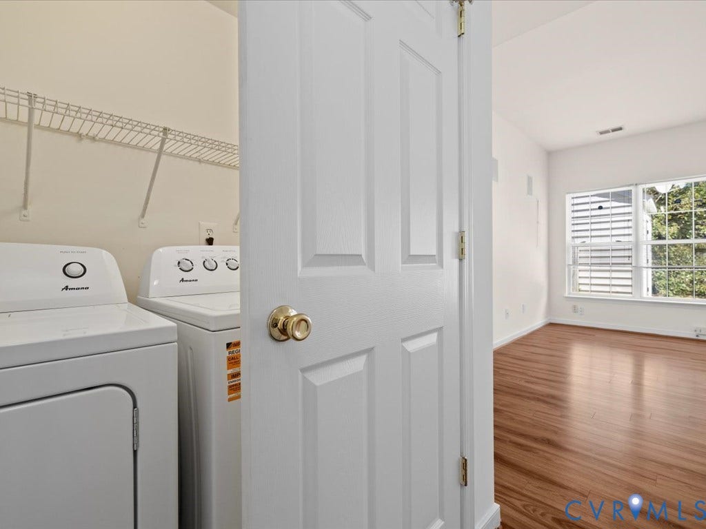 Laundry area with wire shelving, wood-finish flooring, and a large window with white blinds