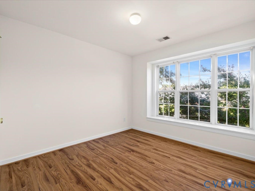 Wood-finish flooring, white walls, and a large multi-pane window