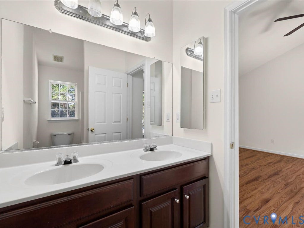 Double vanity with integrated sinks and dark wood-finish cabinetry