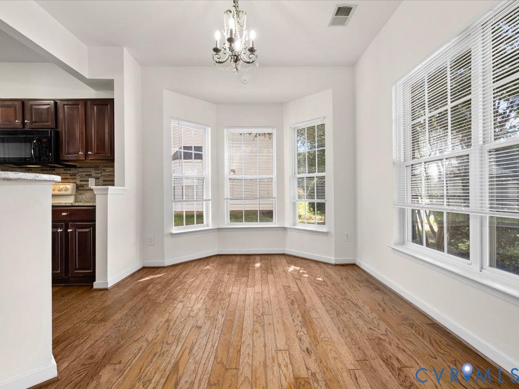 Hardwood flooring throughout, bay window with multiple panes, chandelier lighting, wood cabinetry, and a built-in microwave