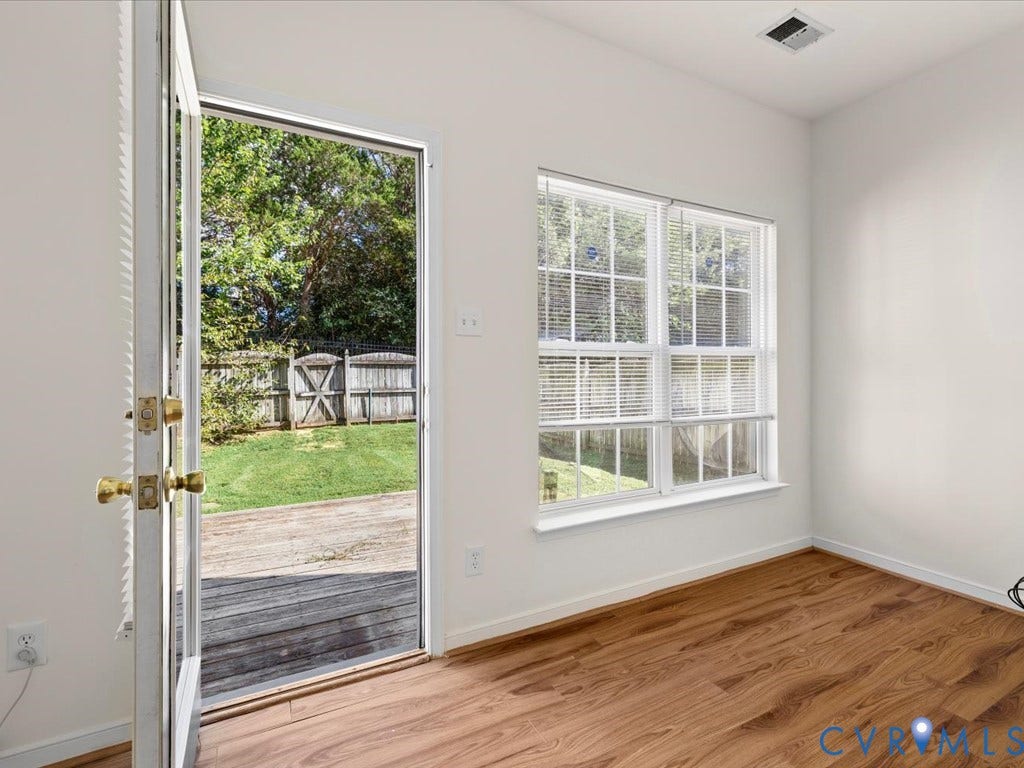 Wood-finish flooring, white walls, and a multi-pane window with blinds