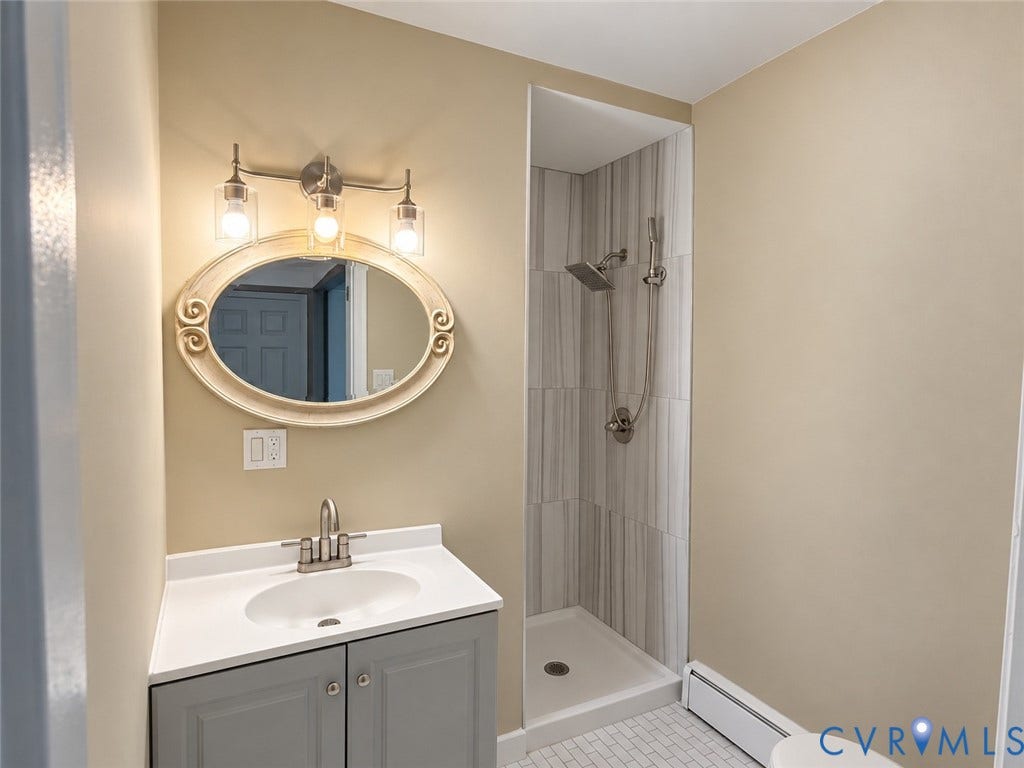 207 S Mesa Drive, Hopewell, VA 23860 Vanity with a white countertop and undermount sink, brushed nickel faucet, and a decorative oval mirror