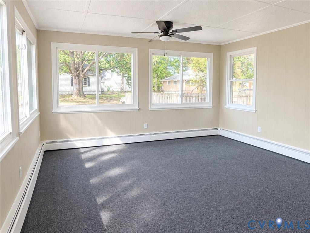207 S Mesa Drive, Hopewell, VA 23860 Neutral tone wall paneling, white trim, multiple windows, dark gray carpeting, and a ceiling fan with light fixture