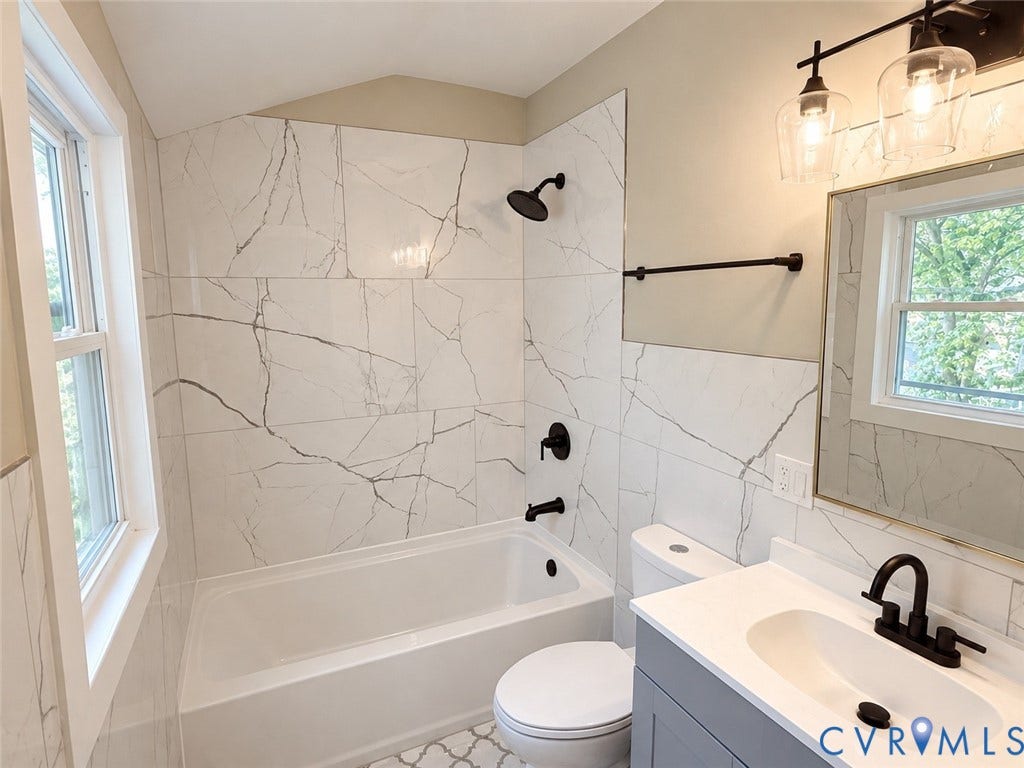 207 S Mesa Drive, Hopewell, VA 23860 Bathroom featuring white subway tile surround with dark veining, black matte fixtures, and a vanity with an integrated sink