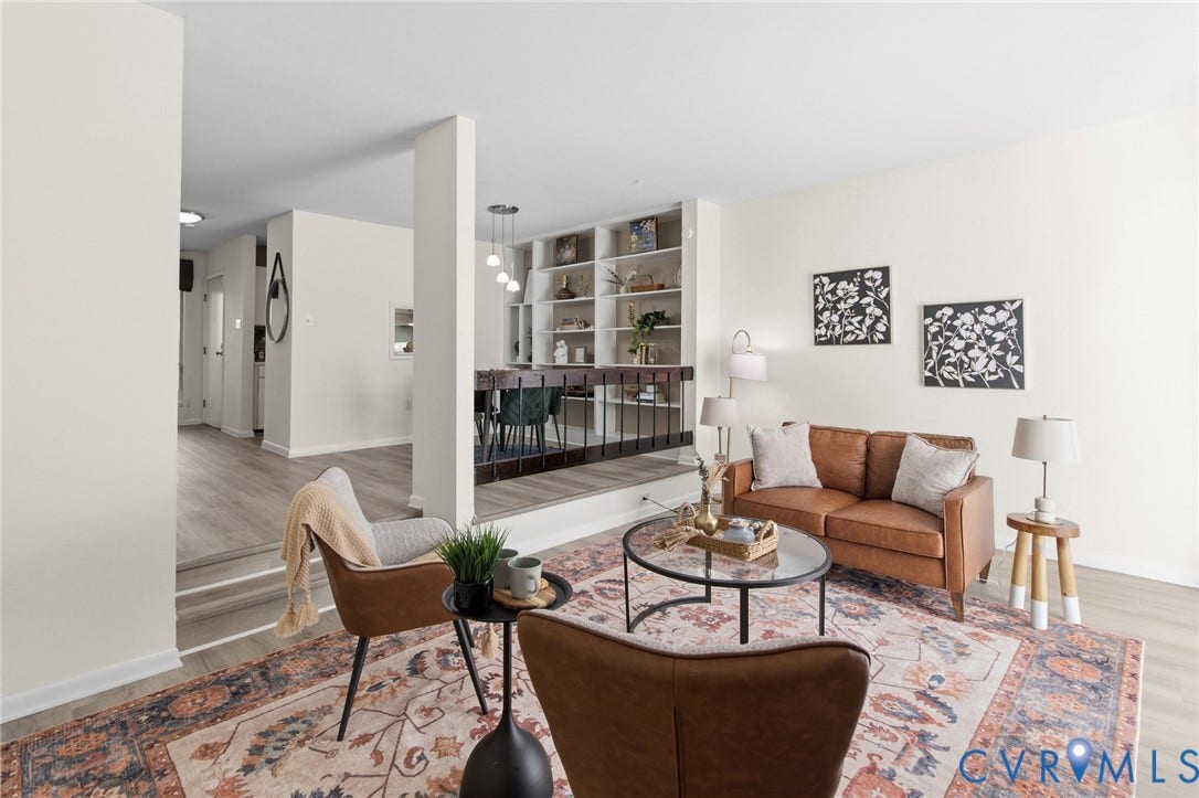 Open-concept living space with light-toned walls, wood-finish flooring, and built-in shelving
