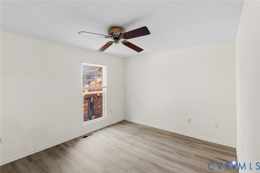 Recessed window with blinds, wood-finish flooring, ceiling fan, and white walls
