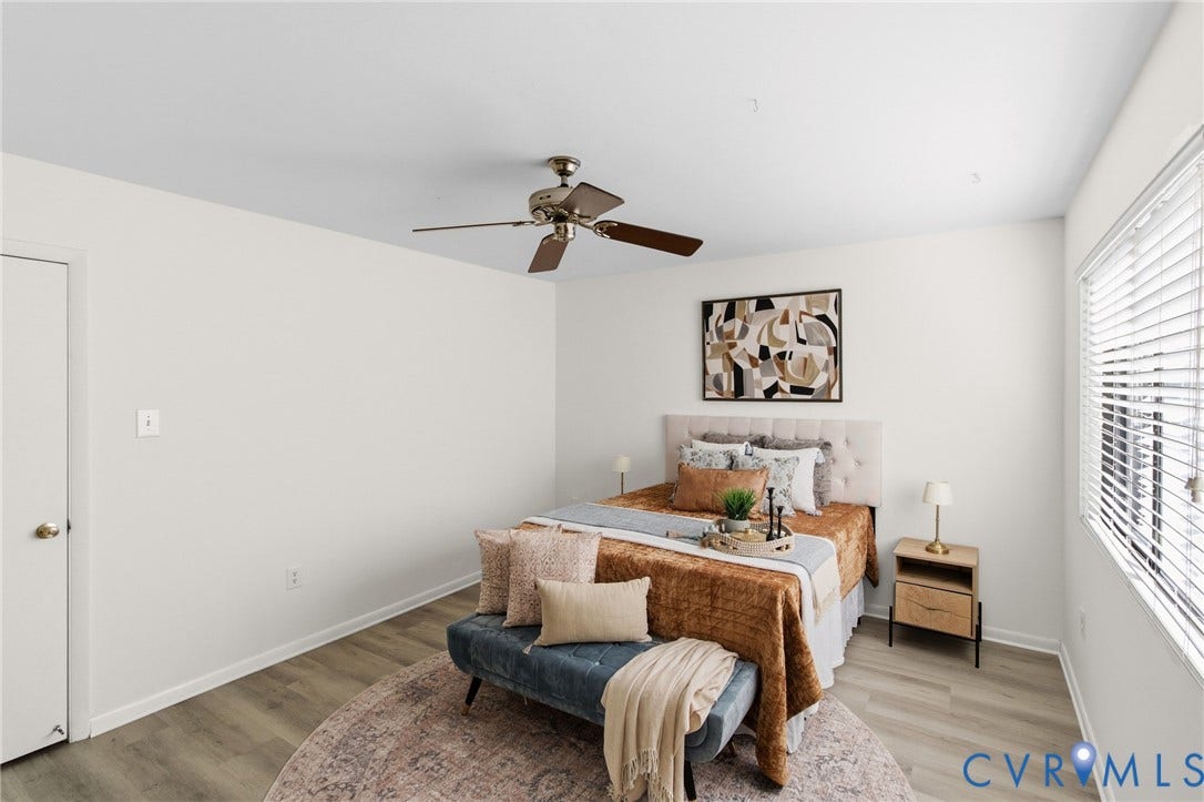 Light wood-finish flooring, ceiling fan with light fixture, and window with horizontal blinds