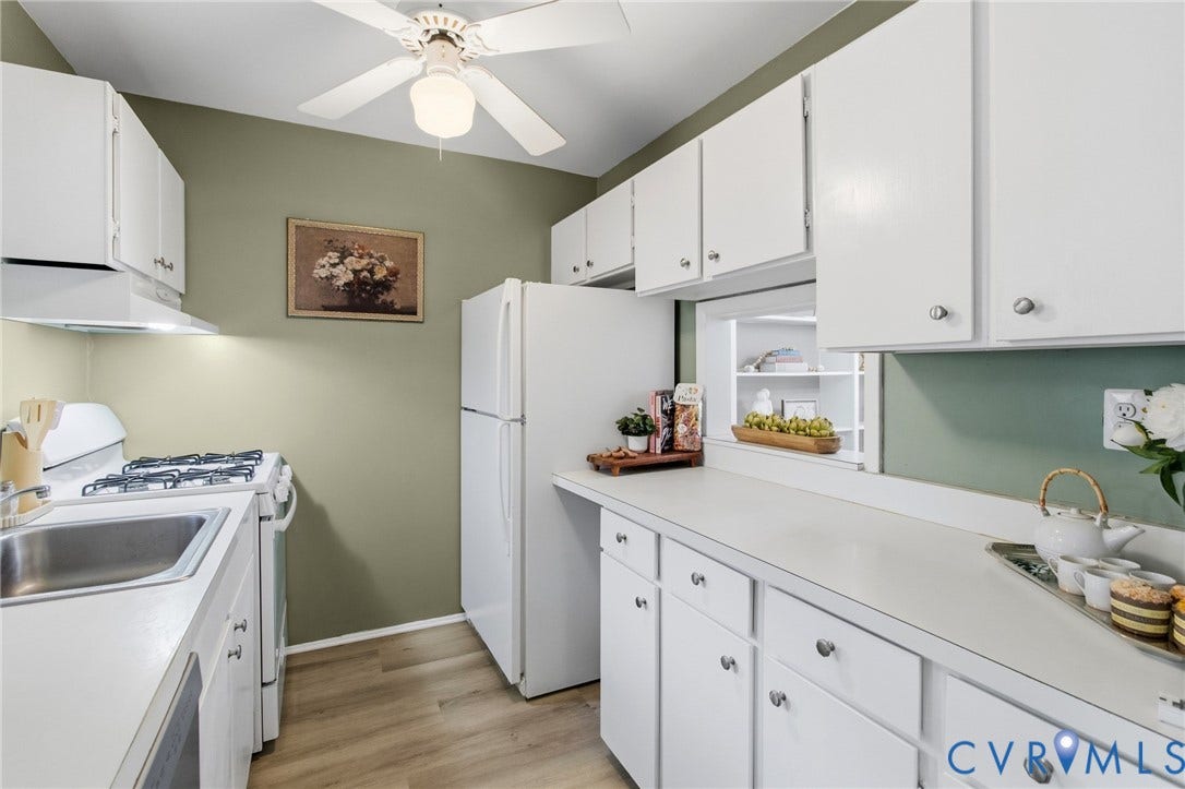 Kitchen featuring white cabinetry, white appliances, a stainless steel sink, wood-finish flooring, and a ceiling fan with integrated lighting