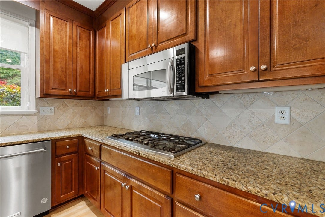 3808 Barrington Branch Court, Henrico, VA 23233 Wood-finish cabinetry, granite countertops, stainless steel appliances, tile backsplash, and a gas cooktop