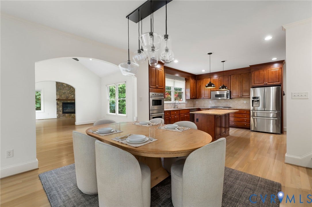 3808 Barrington Branch Court, Henrico, VA 23233 Open-concept living area with hardwood flooring, a kitchen featuring wood cabinetry and stainless steel appliances, and an arched entryway to a room with a stone-clad fireplace