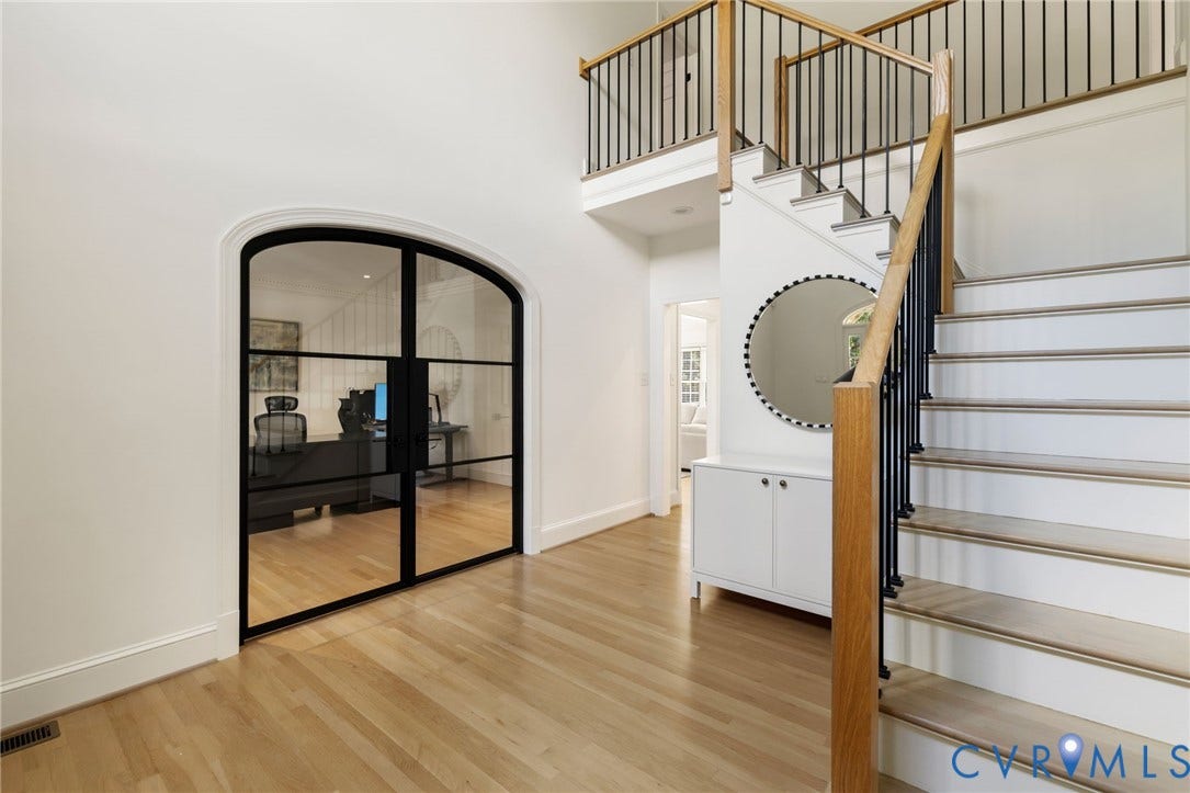 3808 Barrington Branch Court, Henrico, VA 23233 Hardwood flooring extends throughout this space, featuring an arched entryway with black-framed glass doors and a staircase with wood handrails and black balusters