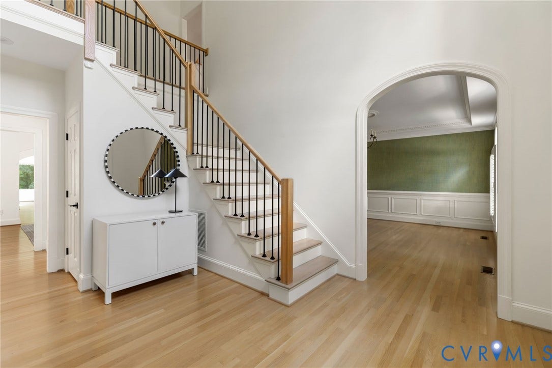 3808 Barrington Branch Court, Henrico, VA 23233 Hardwood flooring throughout, a staircase with wood handrails and black iron balusters, an arched doorway, and wainscoting with crown molding
