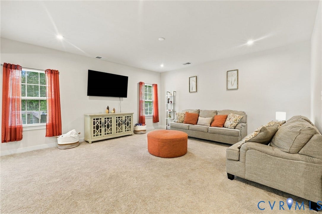 Spacious room with recessed lighting, light-colored carpeting, multiple windows, and a built-in media console