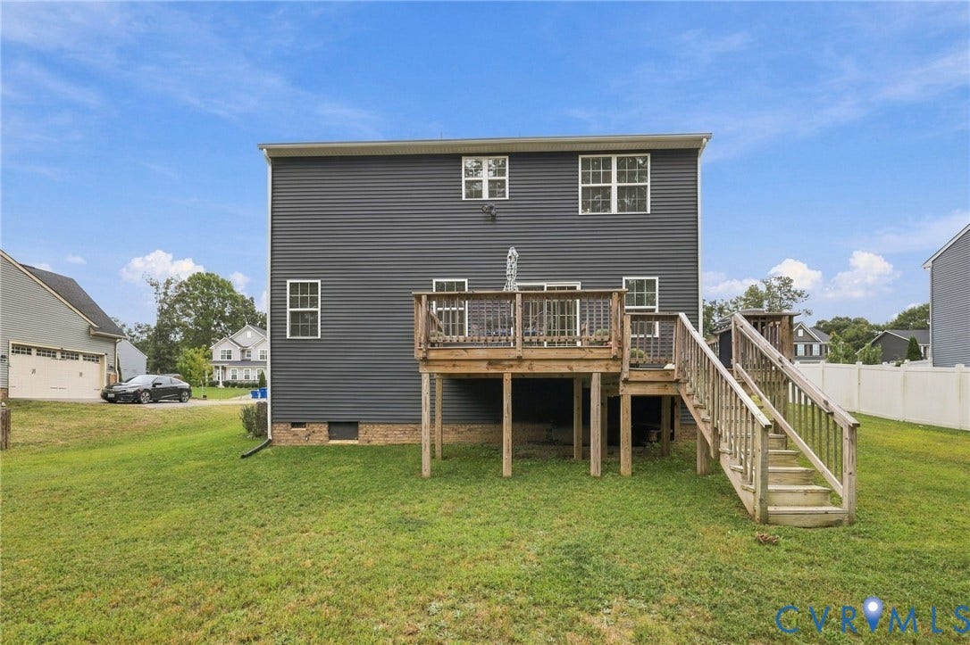 Expansive backyard with a manicured lawn, multi-level wood deck, and wood-finish stairs