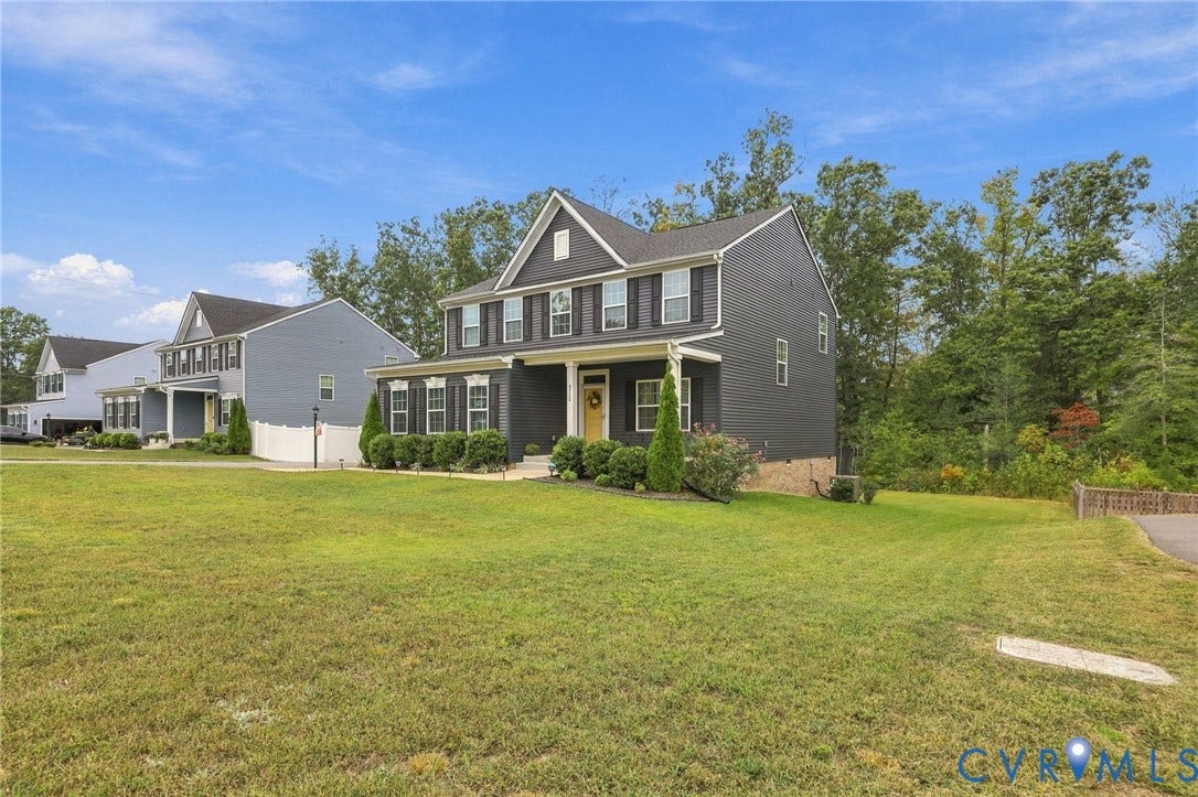 Two-story residence featuring a classic gabled roofline, dark siding, and a covered front porch