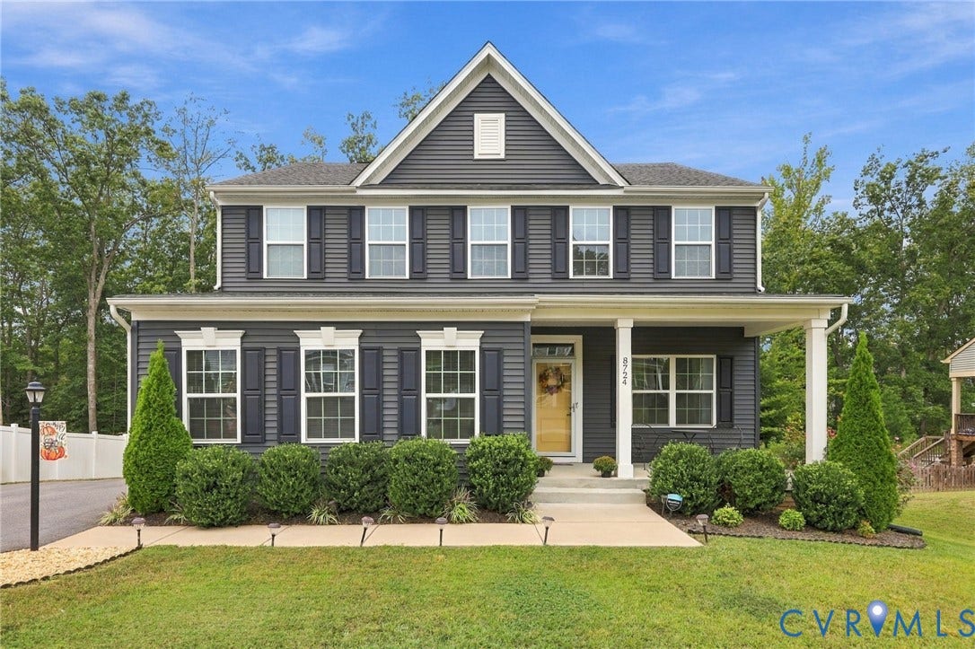 Two-story residential structure featuring dark siding, white trim, and a covered porch with white columns