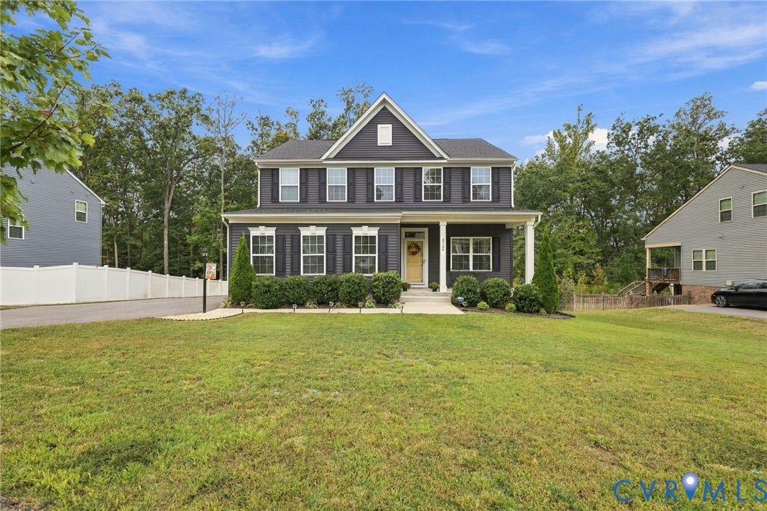 Two-story residence featuring dark siding, white trim, and a prominent front porch with white columns
