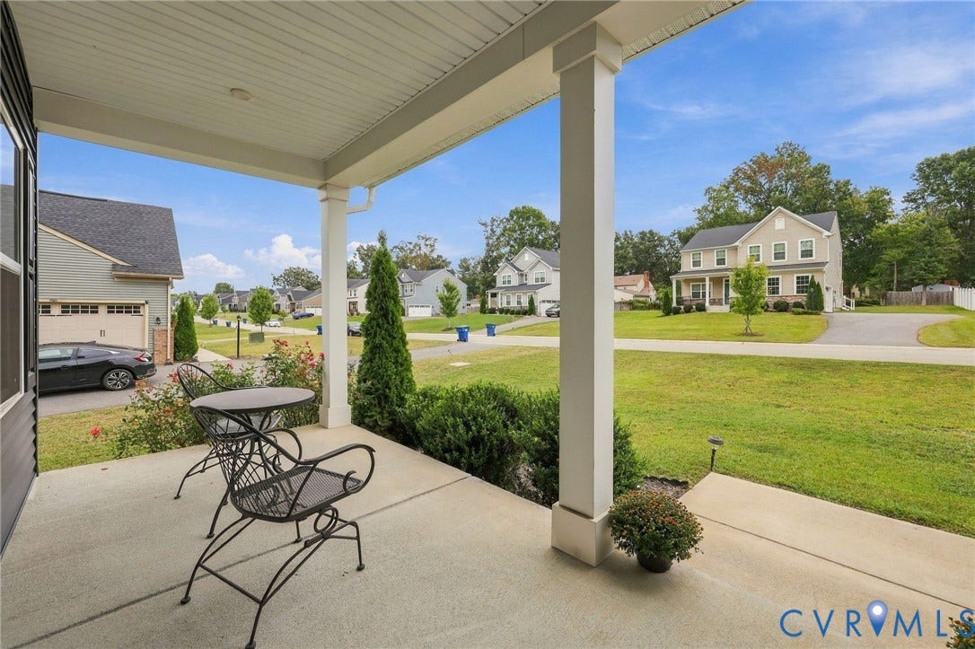 Covered concrete porch with white pillars and a landscaped perimeter