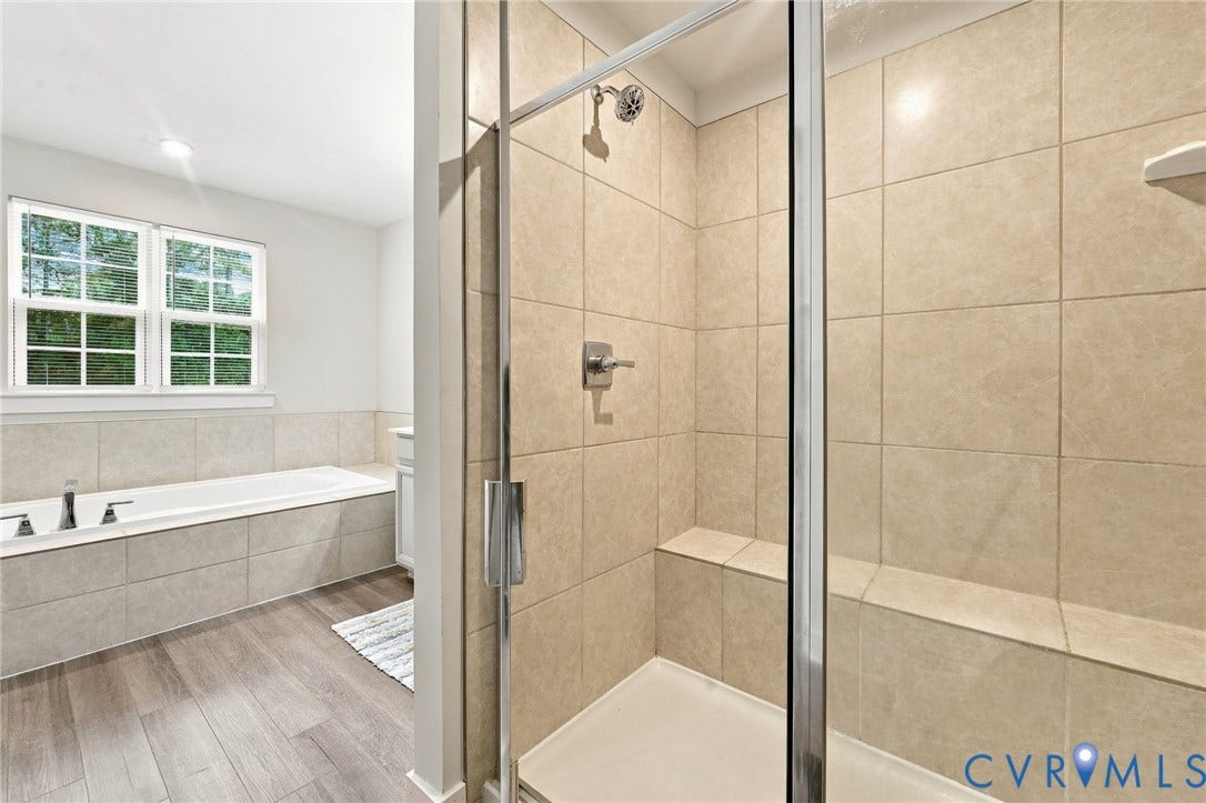 Glass-enclosed shower with a built-in bench, tiled walls, and a chrome shower head