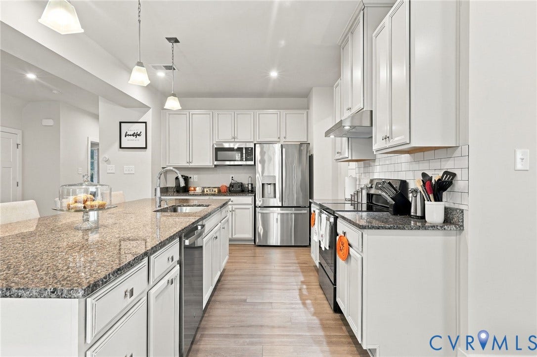 Kitchen featuring wood-finish flooring, white cabinetry, granite countertops, stainless steel appliances, and subway tile backsplash