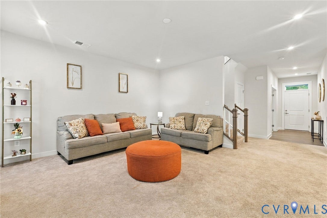 Recessed ceiling lighting, light-toned wall paint, carpet flooring, a white front door, and wood-finish handrails