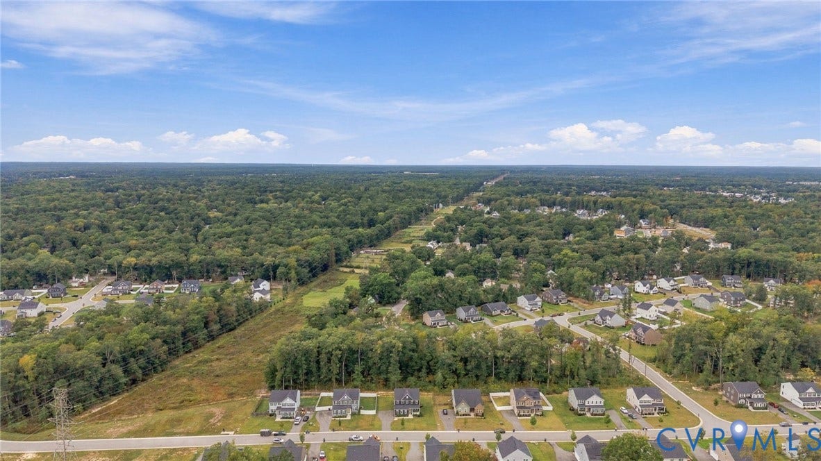 Established residential streets with individual properties, surrounded by extensive wooded areas under a clear sky
