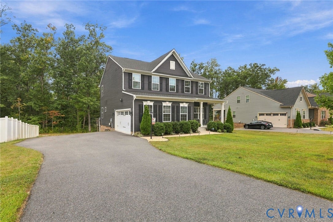Two-story residence with dark siding, white trim, attached two-car garage, and a covered front porch