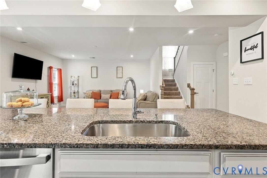 Kitchen island featuring a stainless steel sink and a granite-finish countertop