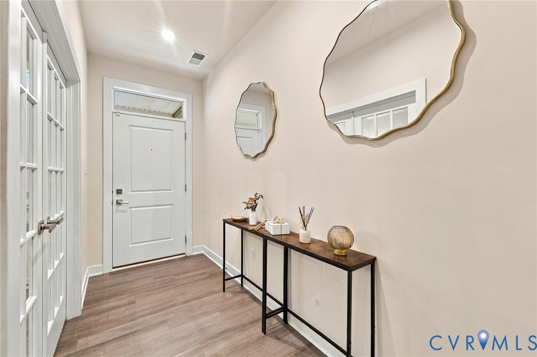 Entryway featuring wood-finish flooring, a solid panel door with a transom window, and a built-in recessed light fixture