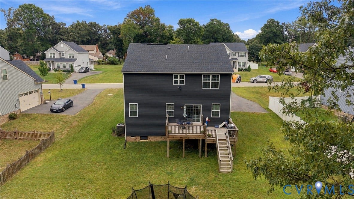 Expansive green yard with a wooden deck and staircase