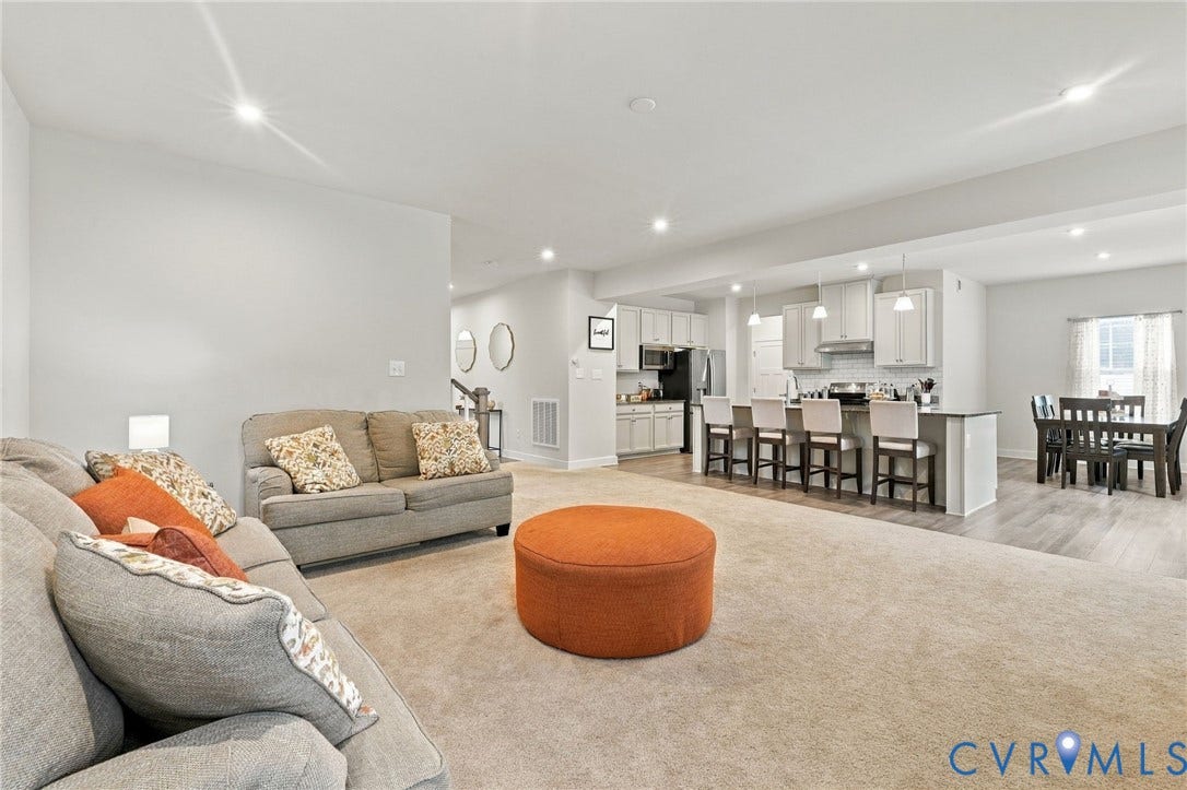 Open-concept living space featuring recessed lighting, a kitchen island with seating, pendant lighting, stainless steel appliances, and wood-finish flooring in the dining area